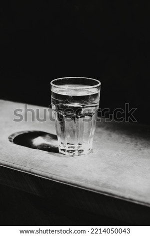 Glass of still water on a dark background. Black and white photography. Minimal concept.Place for text.