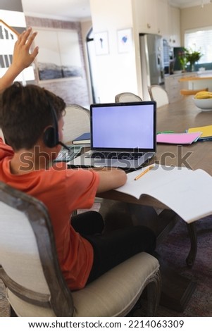 Vertical picture of caucasian boy learning and using laptop with copy space siting in living room. Home educations, distance educations.