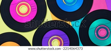 Colorful vinyl CD discs in flat lay banner format displayed on a multicolored background, retro records conceptual image.