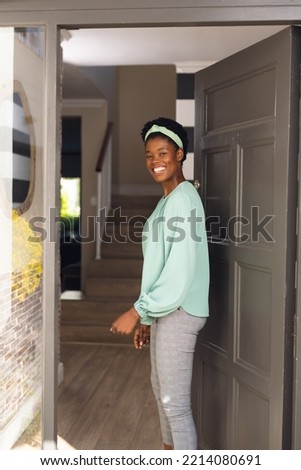 Vertical picture of happy african american women welcoming some body outside the house. Spending time together at home.