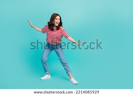 Full length photo of pretty sweet lady wear striped t-shirt having fun riding surf looking empty space isolated turquoise color background