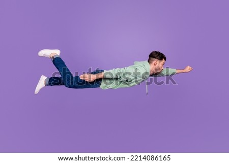 Full body photo of attractive young man flying superman fist confident dressed stylish khaki clothes isolated on purple color background