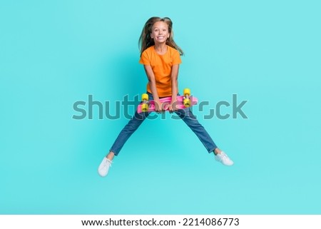 Full length photo of sweet cute small kid wear orange t-shirt rising longboard jumping high isolated turquoise color background