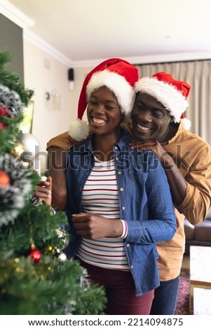 Vertical picture of african american couple spending time together and decorating christmas tree. Christmas, family time and celebration concept.