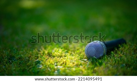 Microphone on a green summer background. An outdoor concert. Performance in nature. Royalty-Free Stock Photo #2214095491