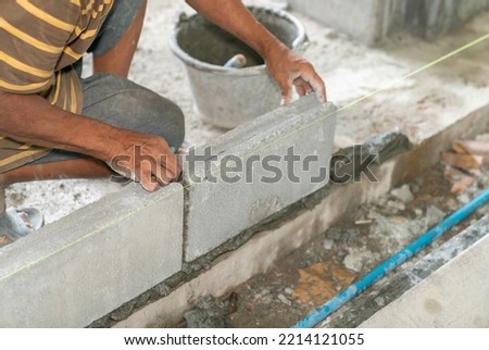 Hand of mansonry install concrete brick for wall of building in construction site.