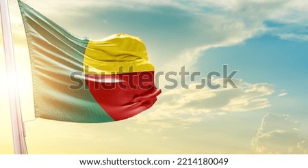 Waving Flag of Benin in Blue Sky. The symbol of the state on wavy cotton fabric.