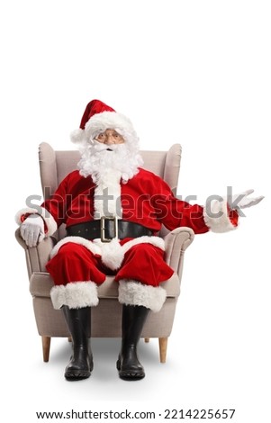 Santa claus sitting in armchair and showing something with hand isolated on white background Royalty-Free Stock Photo #2214225657