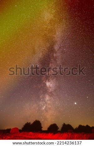 Natural Real Night Sky Stars With Milky Way Over Field Meadow After Harvest. Agricultural Colorful Background Copy Space. Traces Of Meteors On Night Sky.