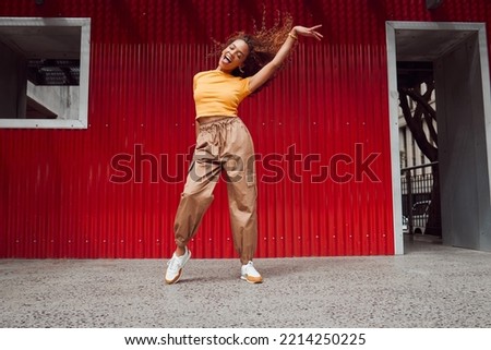 Dance, freedom and fun with a black woman on a red background, dancing or happy with a smile while moving to music. Dancer, free and expression with an attractive young female in rhythmic movement