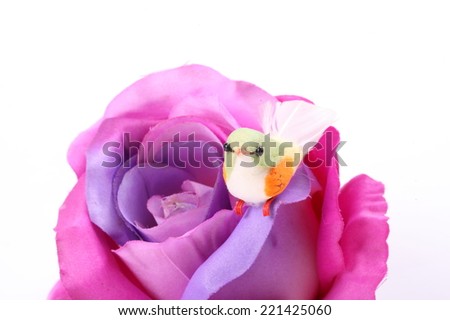 A fake bird and purple textile rose flower 