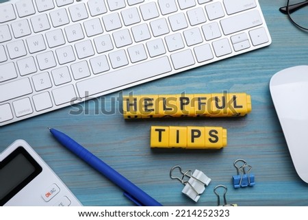 Flat lay composition with text Helpful Tips made of cubes on light blue wooden table