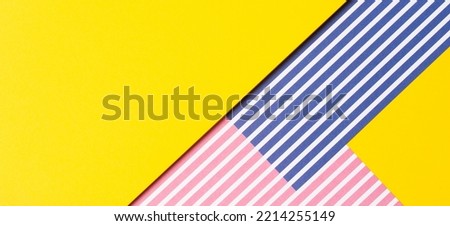 Abstract geometric fashion colored papers texture background. Striped paper with red, blue, white stripes and blank yellow paper background with copy space for text. Top view, flat lay