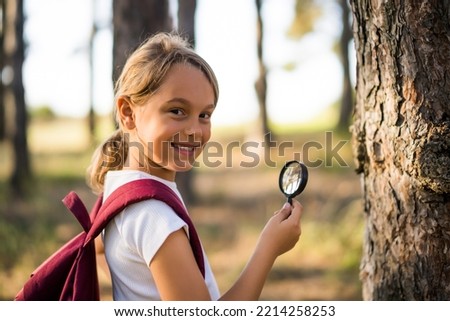 Little girl explore with magnifying glass nature .