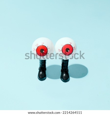 Eyeballs on a pair of combat boots, creative layout against pastel blue background. Monitoring and control idea. 
