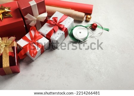 Beautiful Christmas gift boxes wrapped in paper and decorated with bows on light table, space for text