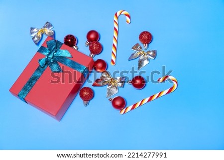 Beautiful Christmas red balls and a red gift with a green ribbon, with lollipops on a blue background. New year christmas concept. Flat lay festive mockup with copy space