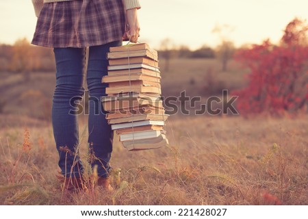 Hipster girl holding a stack of books Royalty-Free Stock Photo #221428027