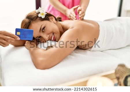 Young latin woman holding credit card having back massage session 