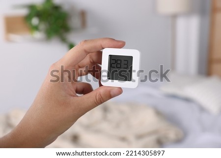 Woman holding digital hygrometer with thermometer indoors, closeup Royalty-Free Stock Photo #2214305897