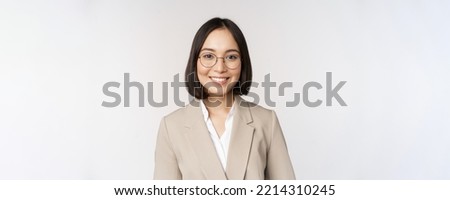 Portrait of young asian saleswoman in glasses, wearing beige suit, smiling and looking confident at camera, white background Royalty-Free Stock Photo #2214310245