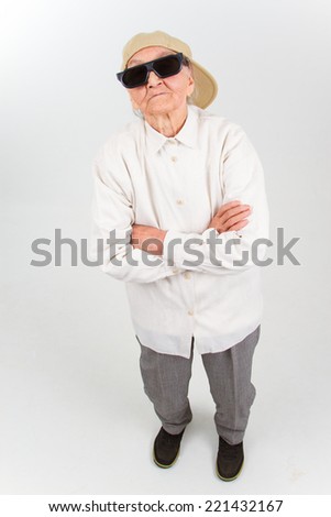 Funny grandma's studio portrait  wearing eyeglasses and baseball cap, who stands for her right,  isolated on white