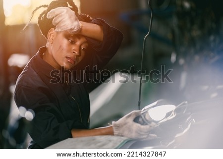 african woman worker hard working tired sweat for mechanic girl engine check garage  Royalty-Free Stock Photo #2214327847