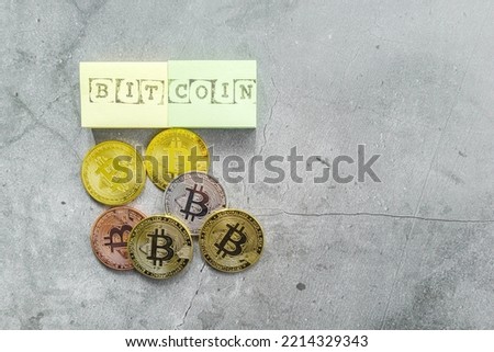 Group of bitcoin tokens with the text Bitcoin on sticky notes, on gray background.