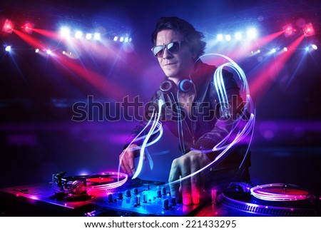 Handsome disc jockey playing music with light beam effects on stage