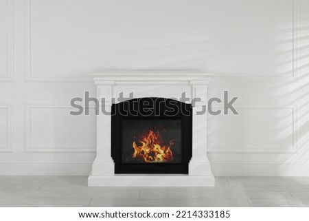 Modern electric fireplace near white wall in room