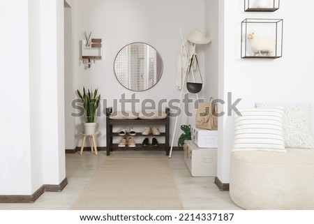 Hallway interior with stylish furniture and round mirror on light wall Royalty-Free Stock Photo #2214337187