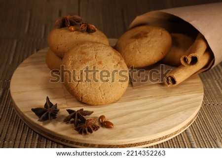 several sweet round cookies with light brown cracks lie on a wooden kitchen brown stand next to spices cinnamon sticks and a few pieces of star anise.for recipe books banner labels