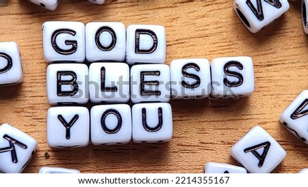 Says God Bless You! written in black letters made of plastic on a wooden background. Concept of God and religious
