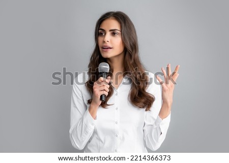 Beautiful business woman is speaking on conference. Young business woman talking with mic. Woman talking with microphone. Communication and information concept.