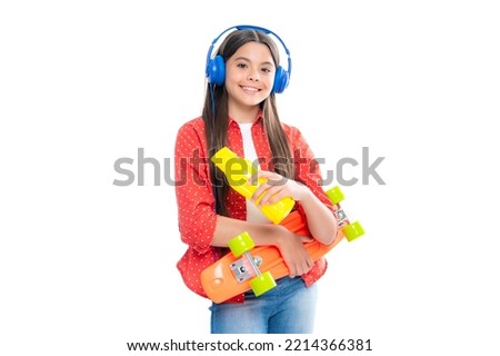 Teenagers lifestyle, casual youth culture. Teen girl with skateboard and headphones over white isolated studio background. Cool modern teenager in stylish clothes. Portrait of happy child girl.