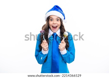 Excited face. Funny child girl on christmas new year hold christmas sweets lollipop isolated in white. Teenager in santa hat. Amazed expression, cheerful and glad.