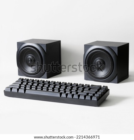 Black mechanical computer keyboard and two square audio speakers on a white background. Concept of an audio recording studio and digital audio broadcasting. Copy space. Selective focus. Close-up