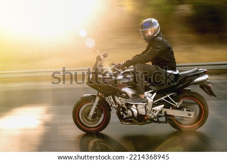 Side view of a biker riding red race motorcycle on the highway with motion blur. 