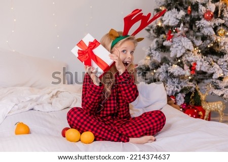 happy little girl in pajamas at home rejoices and unpacks presents for Christmas. High quality photo