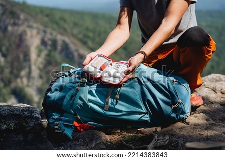 The guy demonstrates the contents of the first aid kit, a box with medicines for an emergency, a set of drugs on a trip, pain pills, a backpack on a hike. High quality photo