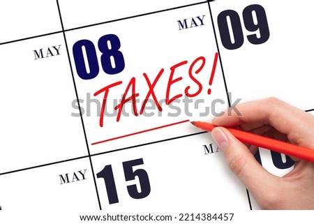 8th day of May. Hand drawing red line and writing the text Taxes on calendar date May 8. Remind date of tax payment. Tax day concept. Spring month, day of the year concept.