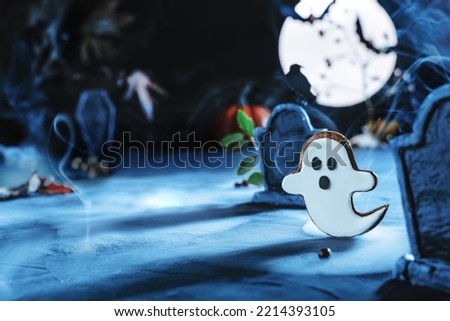 Halloween background with cute ghost flying at night in cemetery between gravestones under the blue light of the moon. Bat silhouettes. Cemetery in the fog. Halloween background, copy space.