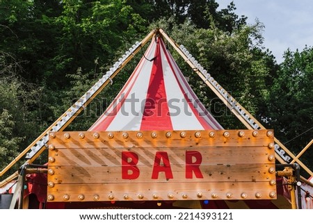 Word BAR at wooden signboard with light bulbs. Vintage sign. Vintage exterior design of bar or pub at food and drink festival. Bar, cafe or restaurant electric sign in retro style with circus tent