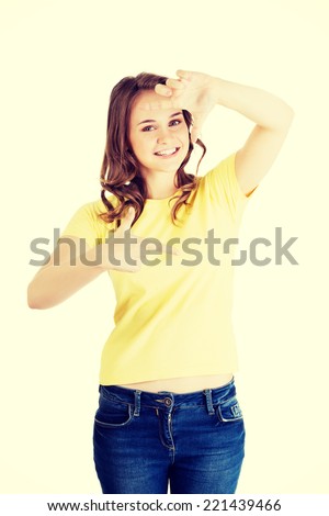 Smiling woman is showing frame by hands. Happy girl with face in frame of palms. Isolated on white background.