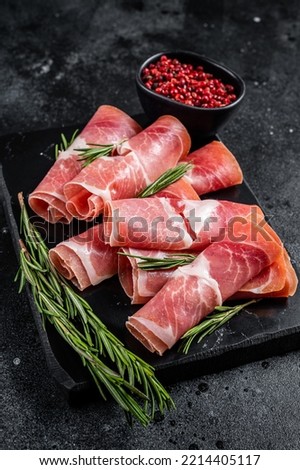 Traditional Spanish Jamon Serrano ham on marble board. Black background. Top view. Royalty-Free Stock Photo #2214405117