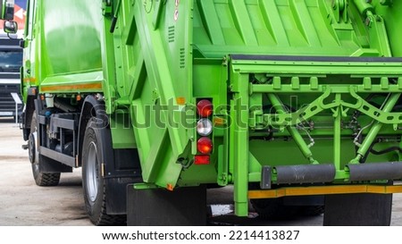 A new modern garbage truck stands on the exhibition area. Rear view of a bright green garbage collection and removal machine. Royalty-Free Stock Photo #2214413827
