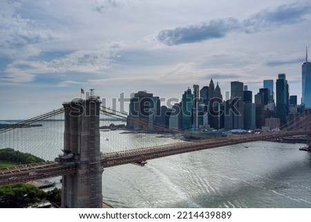 It is panoramic aerial view of Manhattan in the background along East River with picturesque Brooklyn Bridge