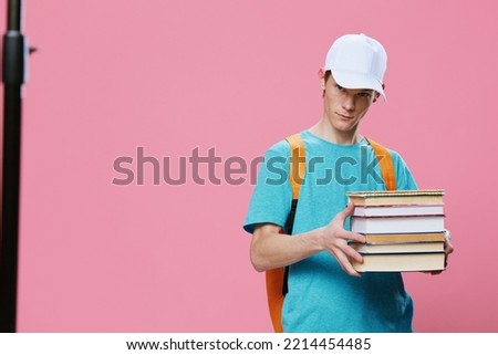 a pleasant, cute student stands with books in his hands with a bright backpack on his back. Preparing for the school season