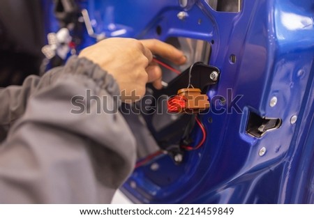 Auto repair technicians in car repair shops are repairing car door systems and repairing electric vehicle systems.