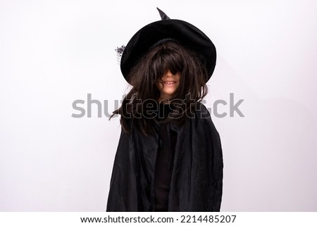 serious Halloween kid on white background covering his face with his hair. Child in black sorcerer's costume with long hair mysterious Witch Trick or treating cheerfully Boy in suit wizard Copy space